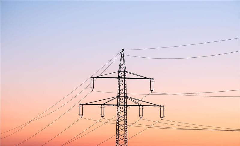 Stromsteuer-Senkung für Industrie teuer als geplant Ein Strommast bei Sonnenaufgang.