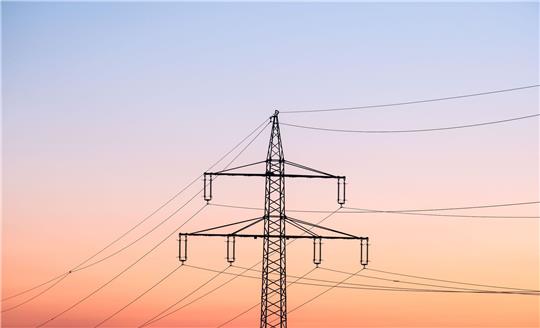 Ein Strommast bei Sonnenaufgang.