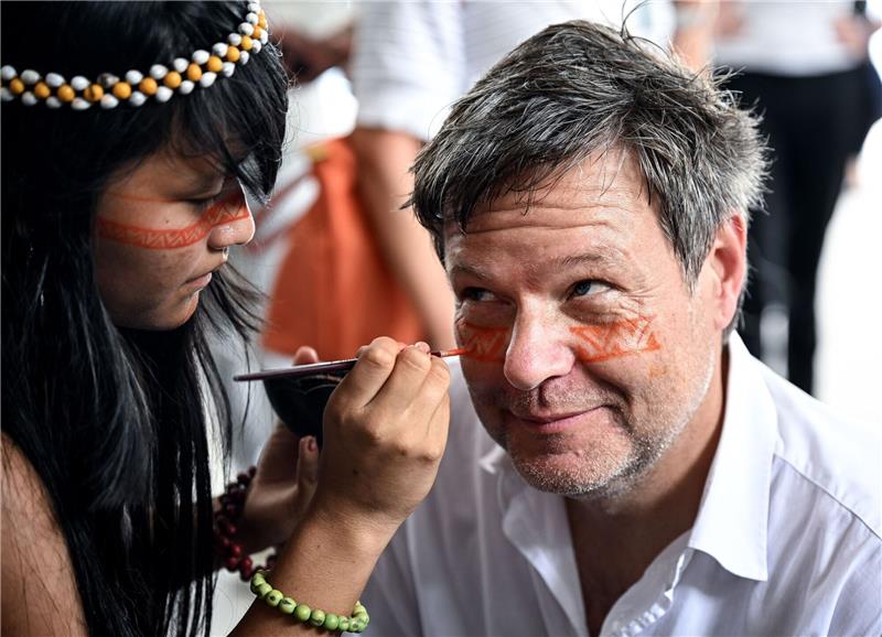 Ein Symbol des Willkommens und des Schutzes: Ein Mädchen malt Bundeswirtschaftsminister Robert Habeck mit einer rötlichen Naturfarbe ein Zeichen unter die Augen.