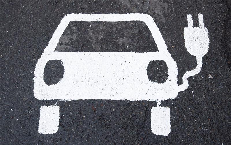 Ein Symbol für ein Elektroauto markiert einen Parkplatz neben einer E-Ladesäule.