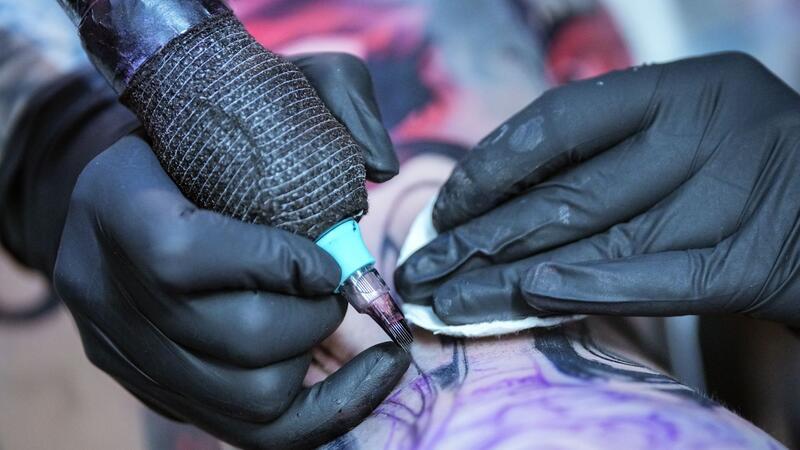 Ein Tätowierer ist bei der Arbeit.