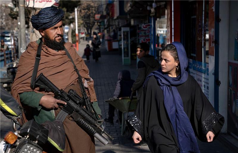 Acht Männer und eine Frau in Afghanistan ausgepeitscht Ein Taliban-Kämpfer steht in Kabul Wache, während eine Frau vorbeiläuft. (Archivbild)