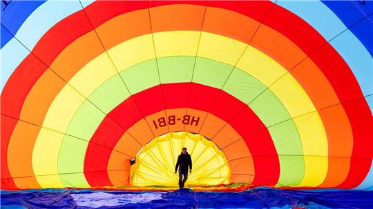 Ein Teammitglied überprüft seinen Heißluftballon vor dem Start während des 46. Internationalen Heißluftballon-Festivals in Chateau-d’Oex.