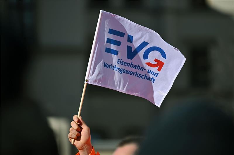 Ein Teilnehmer am Warnstreik Ende März vor dem Erfurter Hauptbahnhof mit einem Fähnchen der Eisenbahn- und Verkehrsgewerkschaft (EVG).