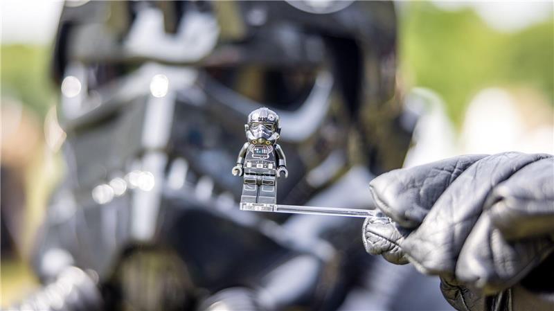 Ein Teilnehmer des Elbenwald Festivals, als Mitglied der Stormtroopers verkleidet, hält eine Figur seiner Rolle vor seinen Kopf.