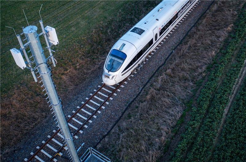 Mobilfunk auf Reisen: Start von 5G-Testfahrten an Zugstrecke Ein Testzug der Deutschen Bahn fährt an einer der Antennenmasten für das 5G-Bahnprojekt vorbei.