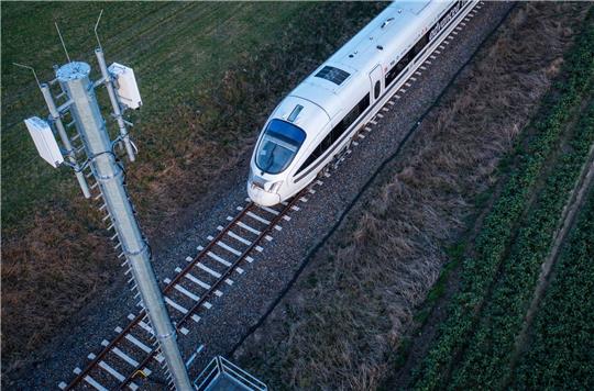 Ein Testzug der Deutschen Bahn fährt an einer der Antennenmasten für das 5G-Bahnprojekt vorbei.