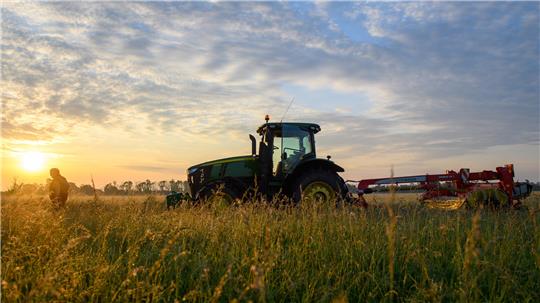 Ein Traktor steht vor der aufgehenden Sonne auf einem Feld. Im Oktober ist Pächterwechsel bei Goslarer Landwirten angesagt.