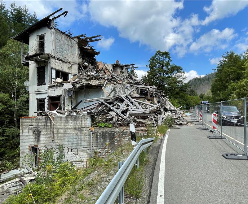 Die Trümmer eines Hauses liegen am Straßenrand hinter einer Absperrung.