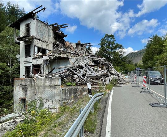 Die Trümmer eines Hauses liegen am Straßenrand hinter einer Absperrung.