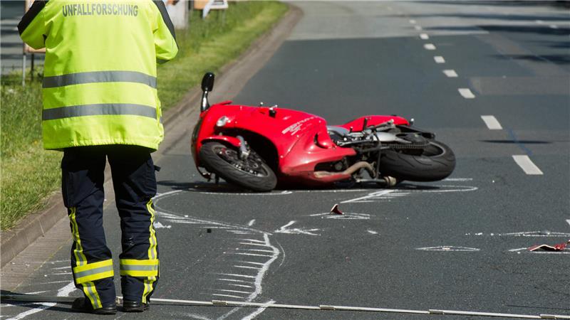 Ein Unfallforscher untersucht ein Motorrad an einer Unfallstelle.