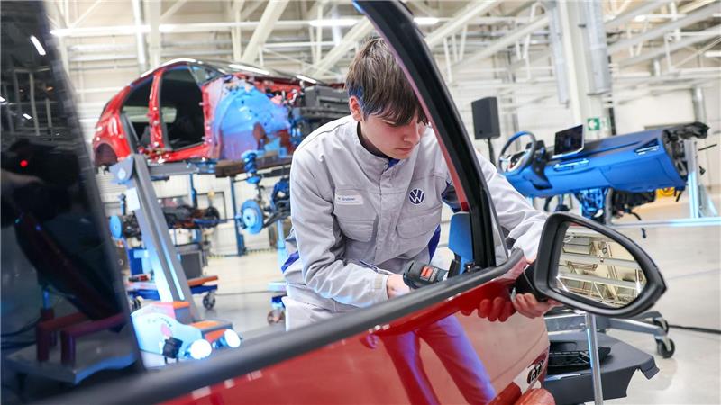 Ein VW-Mitarbeiter demontiert den Außenspiegel aus einem zerlegten VW ID.3. Künftig sollen im Zwickauer VW-Werk auf diese Weise Originalteile für die Reparatur und Aufbereitung von Gebrauchtwagen gewonnen werden. 