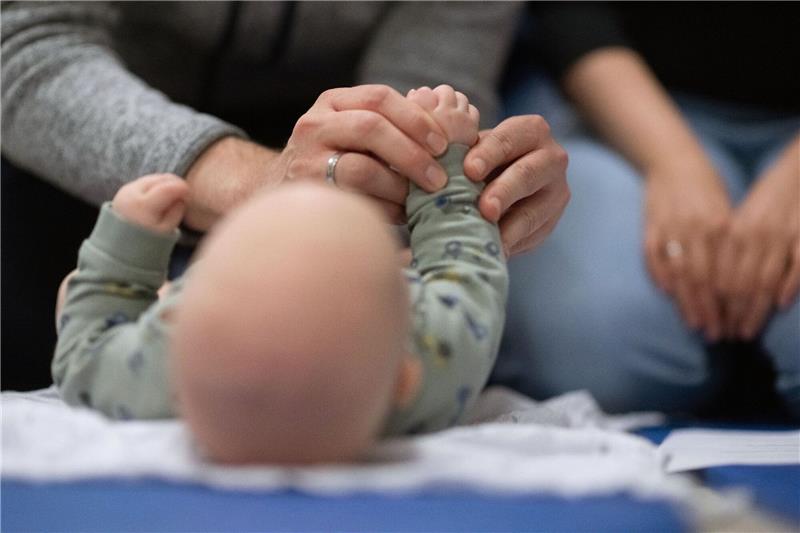 Nur noch knapp jeder Zweite lebt in einer Familie Ein Vater hält während eines Infant Handling Kurses die Füße seines Kindes, während die Mutter daneben sitzt.