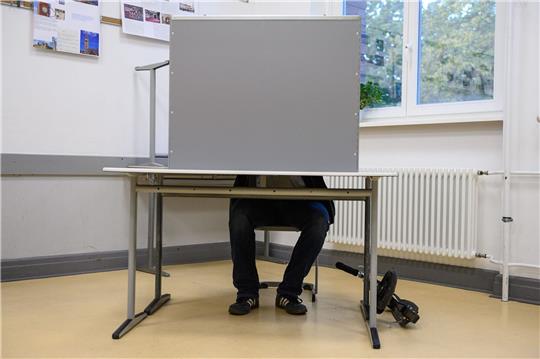 Ein Wähler sitzt hinter einem Sichtschutz im Wahlraum des Felix-Klein-Gymnasium.