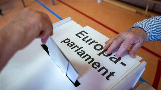 Ein Wahlberechtigter wirft in einem Wahllokal seinen Stimmzettel in eine Wahlurne mit der Aufschrift „Europaparlament“.