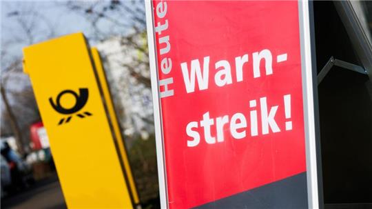 Ein Warnstreik-Schild bei einem Post-Standort, daneben ein Briefkasten - im Ringen um einen Tarifabschluss haben Tausende Postler erneut die Arbeit niedergelegt.