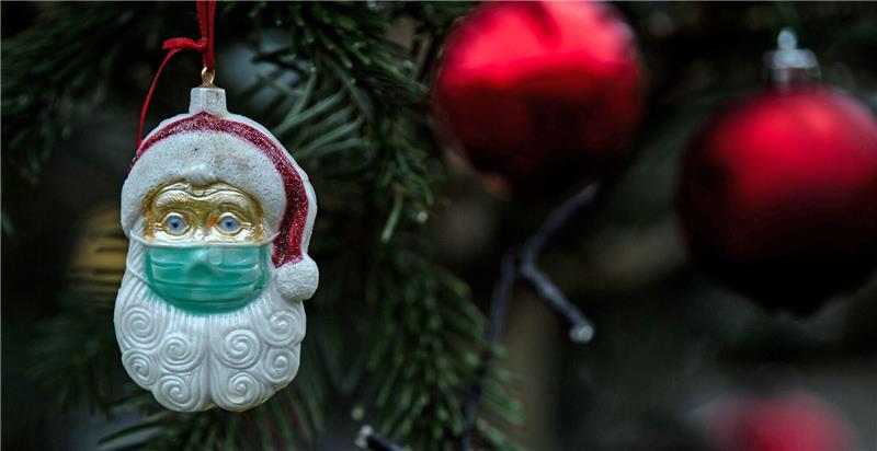 Weihnachten mit Maske? - Grippefallzahlen weiterhin hoch Ein Weihnachtsmann mit einer Schutzmaske hängt als Weihnachtsbaumschmuck in einem Tannenbaum.