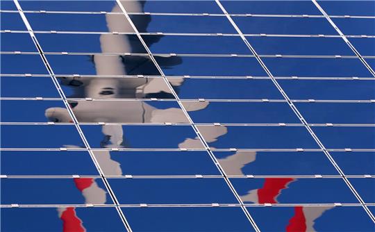 Ein Windrad spiegelt sich in eine Solar-Anlage eines Solarparks in Bayern: Vor allem Solaranlagen spielen in Bayern eine große Rolle.