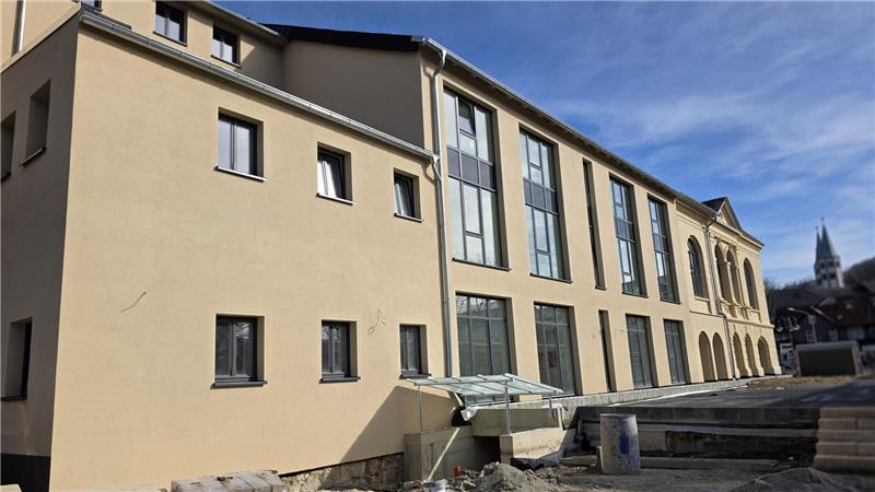 Mehrstöckiges Gebäude mit großen Fenstern und Baustelle im Vordergrund unter blauem Himmel