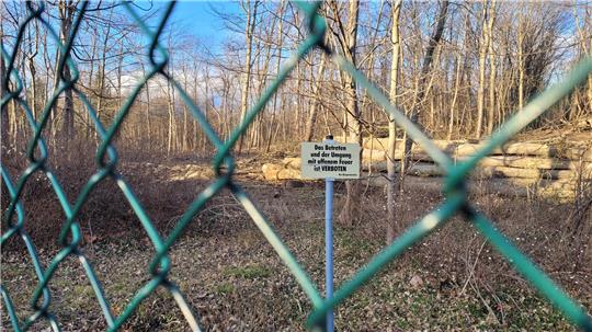 Ein Zaun umschließt die ehemalige Deponie, Warnschilder weisen auf das Betretungsverbot hin.