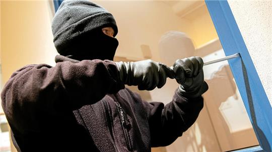 Ein als Einbrecher verkleideter Mann hebelt in der Kriminalpolizeilichen Beratungsstelle der Polizei ein Fenster auf. (Symbolfoto)