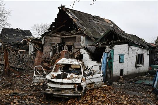 Ein beschädigtes Auto aus der Sowjet-Ära der Marke Saporoshez ist neben einem zerstörten Wohnhaus zu sehen.