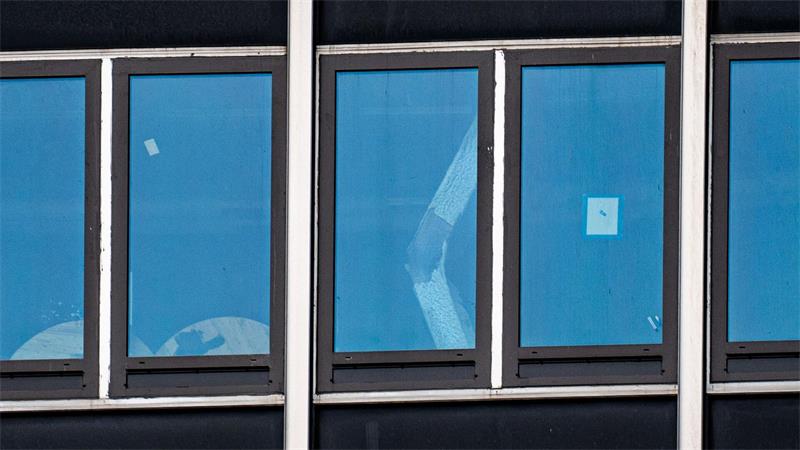 Ein eingeknickter Stützpfeiler ist durch ein Fenster zu sehen.