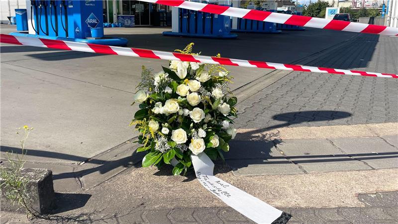 Erschossener Polizist - „Es sind dunkle Tage für unser Land“ Ein großer Blumenkranz steht vor der überfallenen Tankstelle.