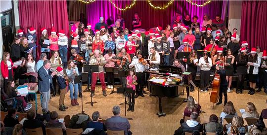 Ein großes Ensemble aus Schülern, Lehrern und externen Unterstützern stimmt die Gäste bei einem musikalischen Abend auf die Weihnachtszeit ein.