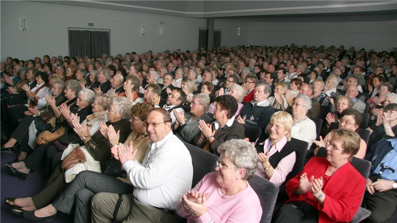 Große Gruppe von Menschen in einem Saal, die applaudieren

