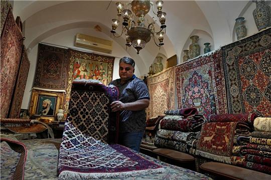 Ein iranischer Teppichhändler arbeitet in seinem Geschäft auf dem traditionellen Basar der Stadt Kashan.