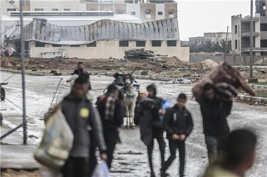 Ein israelischer Panzer ist zu sehen, während Palästinenser das Nasser-Krankenhaus und die angrenzenden Schulen verlassen.