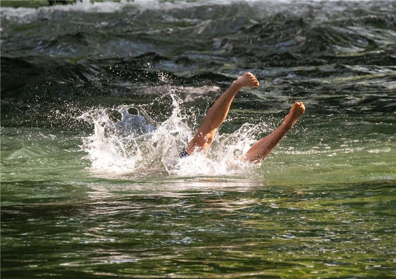 Ein junger Mann in München erfrischt sich mit einem Sprung in den Eisbach im Englischen Garten.