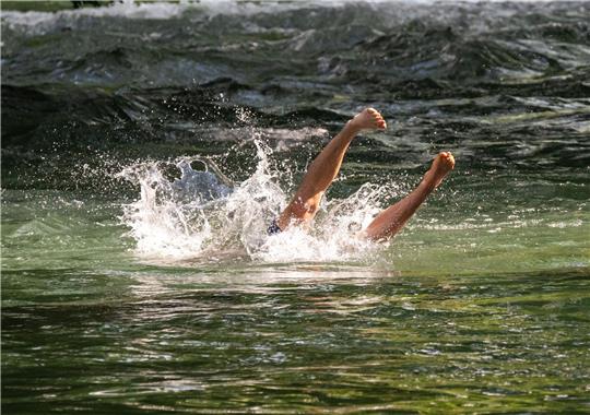 Ein junger Mann in München erfrischt sich mit einem Sprung in den Eisbach im Englischen Garten.