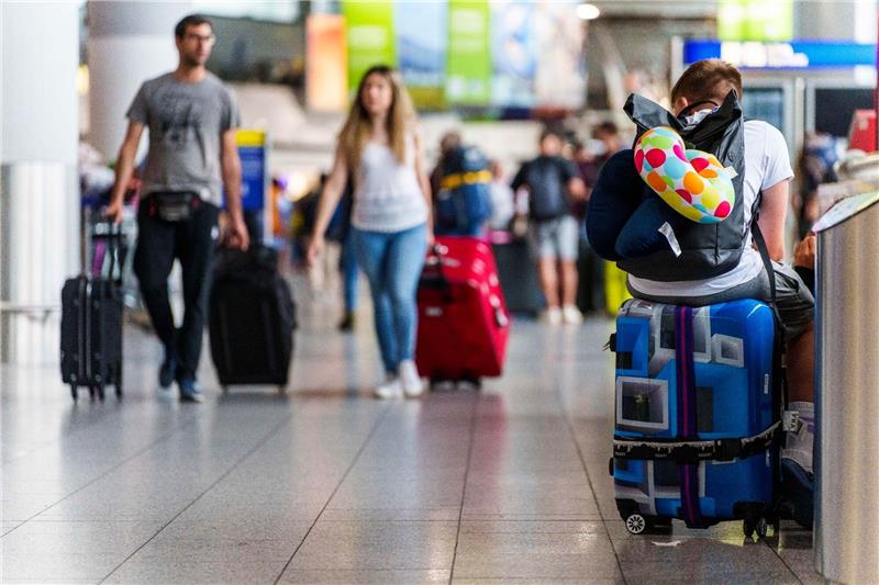 Starkregen über Frankfurt führt zu Dutzenden Flugausfällen Ein junger Mann ruht sich auf seinem Koffer im Flughafen Frankfurt Main aus.