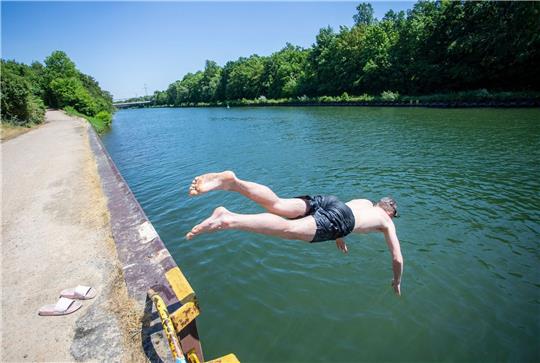 Ein junger Mann springt bei hochsommerlichem Wetter in den Rhein-Herne-Kanal.