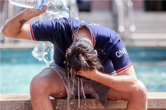 Ein junger Mann übergießt sich mit einer Wasserflasche, um die Hitze zu bekämpfen. Foto: Ricardo Rubio / pa/dpa