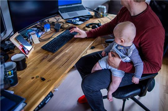 Ein junger Vater im Home-Office mit seinem sechs Monate alten Sohn.