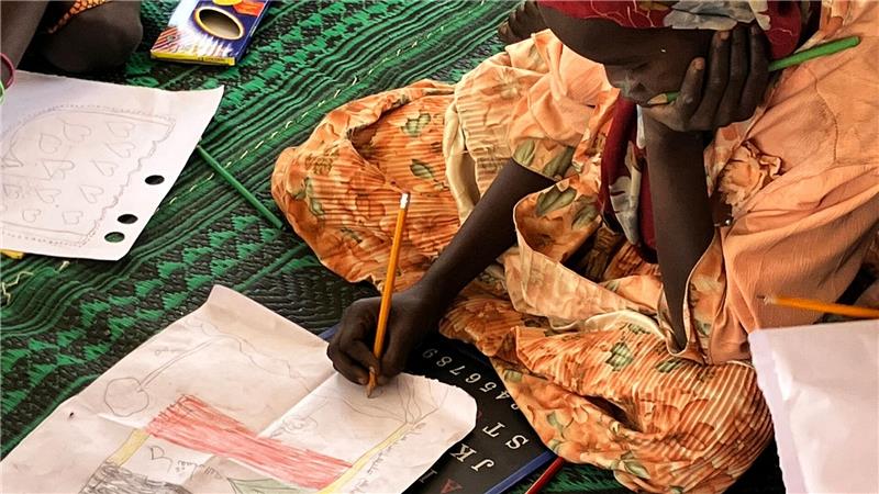 Sudans vergessenes Leid: Leben im Stillstand nach der Flucht Ein kleines Mädchen malt die sudanesische Flagge.