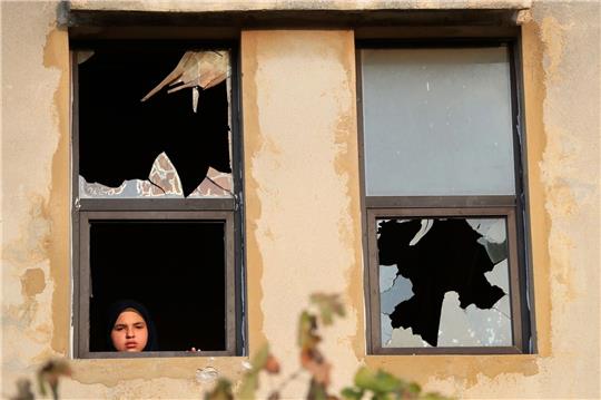Ein libanesisches Mädchen blickt nach israelischem Beschuss auf ein Dorf im Südlibanon durch ein zerbrochenes Fenster.