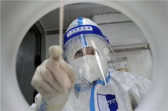 Ein medizinischer Mitarbeiter in Schutzkleidung während er einen PCR-Test zum Nachweis des Coronavirus durchführt.