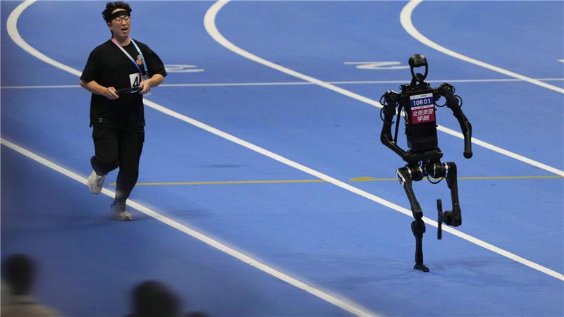 Bilder des Tages Ein menschlicher Bediener versucht, mit einem Roboter im 1500-Meter-Lauf bei den World Humanoid Robot Games in Peking Schritt zu halten.