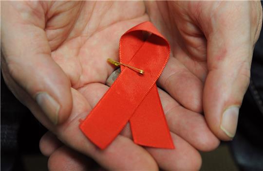 Ein mit dem HI-Virus infizierter Mann mit einer roten Schleife als Symbol der Solidarität mit HIV-Positiven und Aids-Kranken.