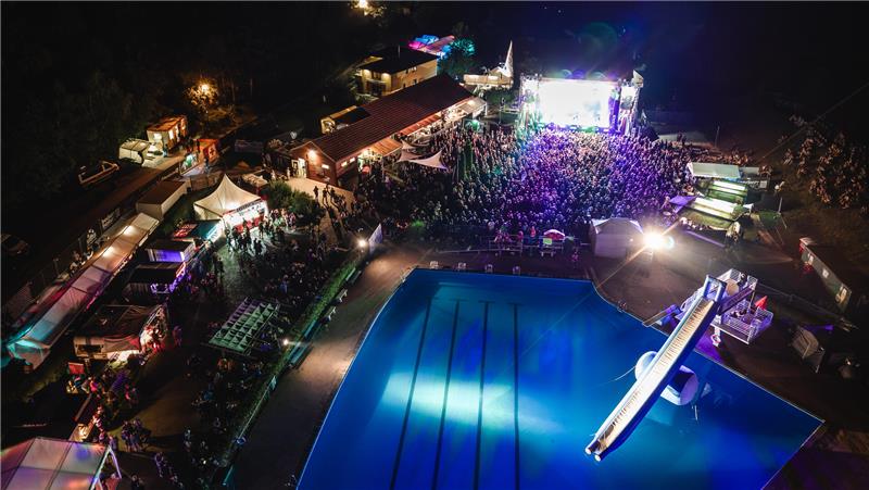 Das bunt beleuchtete Festivalgelände von oben betrachtet. Bei Nacht.