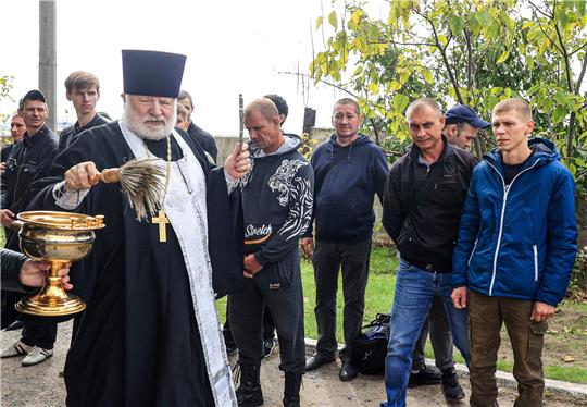 Ein orthodoxer Priester segnet in der südrussischen Stadt Wolgograd zum Militär eingezogene Männer. Foto: Rogulin/dpa/TASS