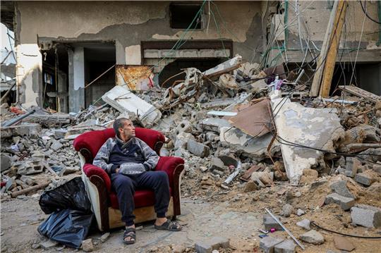 Ein palästinensischer Mann sitzt in einem Sessel vor einem zerstörten Gebäude in Gaza-Stadt.