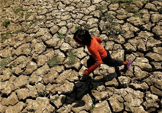 Ein philippinisches Kind läuft in der Provinz Cavite auf den Philippinen in einem ausgetrockneten Bewässerungskanal, der durch das Wetterphänomen "El Niño" ausgetrocknet war.