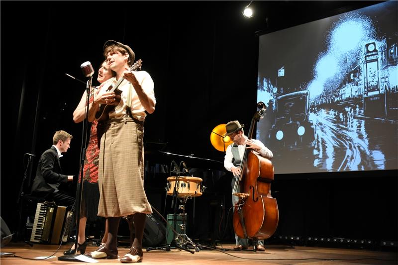 „Ein rätselhafter Schimmer“ lautet der Titel des Zwanziger-Jahre-Programms, vom Trio Größenwahn und dem Zeichner Robert Nippoldt virtuos und augenzwinkernd auf die Bühne des Kulturkraftwerks Harzenergie gebracht. Beim Couplet „Schöner Gigolo“ steuert Nippoldt (vorne) den Ukulelenpart bei. Foto: Kempfer
