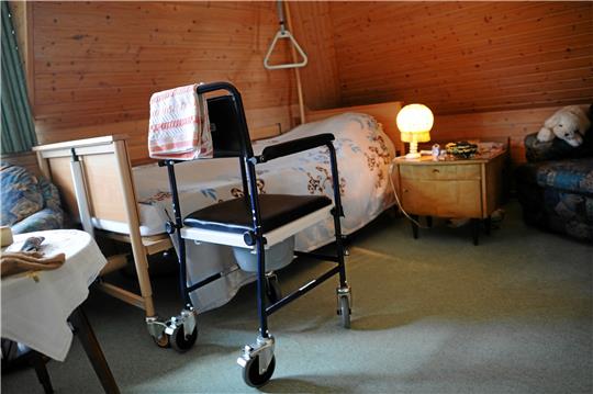 Ein rollbarer Toilettenstuhl steht in einem Zimmer in einer Pflege-Wohngemeinschaft: Die häusliche Krankenpflege befindet sich derzeit in einer wirtschaftlich schwierigen Situation. Foto: dpa