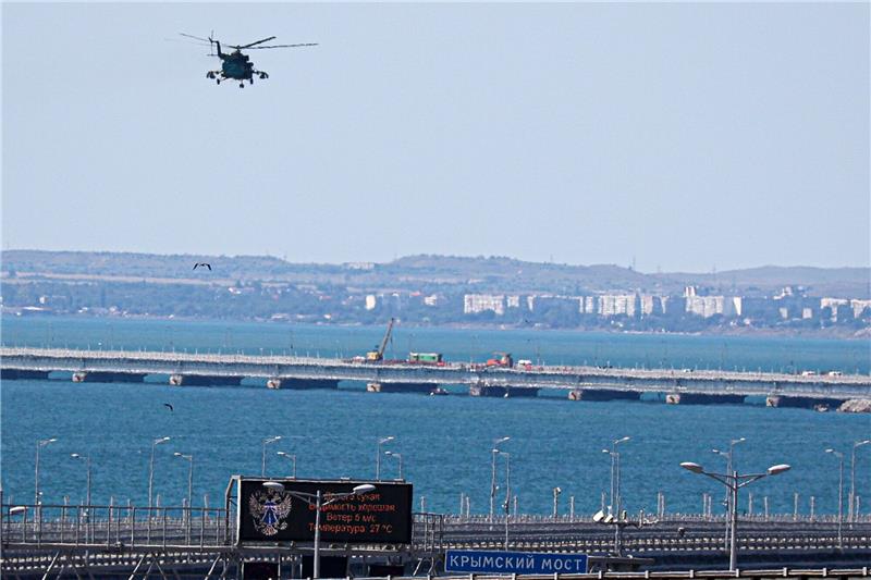 Ein russischer Militärhubschrauber überfliegt die beschädigten Teile einer Automobilverbindung der Krim-Brücke.